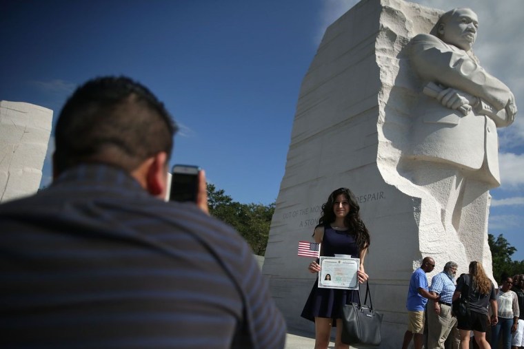 Judith Escobar, oriunda de El Salvador, posa con su certificado de naturalización como ciudadana de EE.UU. y una bandera estadounidense frente al monumento de Martin Luther King Jr. en Washington DC durante un día despejado de agosto, en 2015