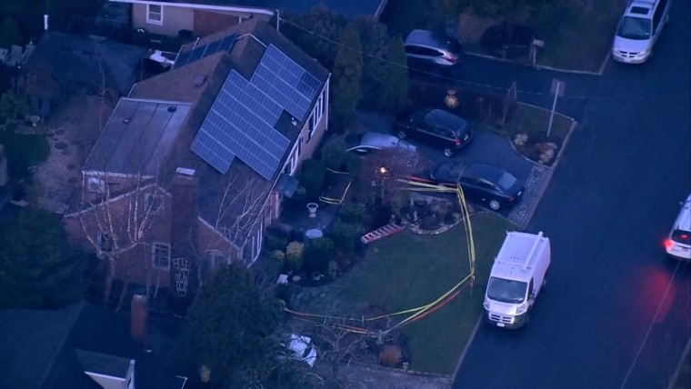 A house with solar panels is roped off with yellow caution tape and a sinkhole is visible next to the driveway