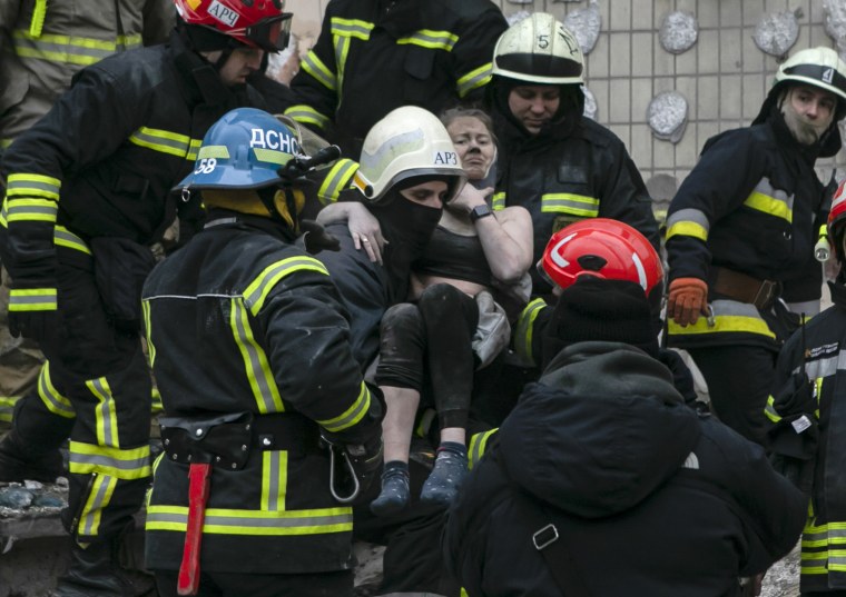 Trabajadores de emergencia trasladan a una mujer herida un día después del impacto de un cohete ruso contra un edificio de varios pisos el sábado en Dnipro, Ucrania.