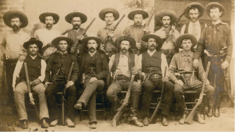 Fotografía en sepia de un grupo de 14 hombres integrantes de los Texas Rangers
