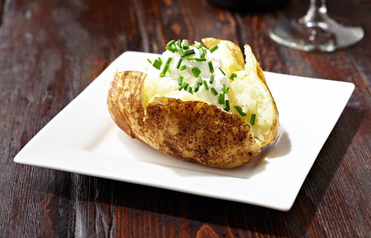 Baked potato on a dark rustic wooden table.