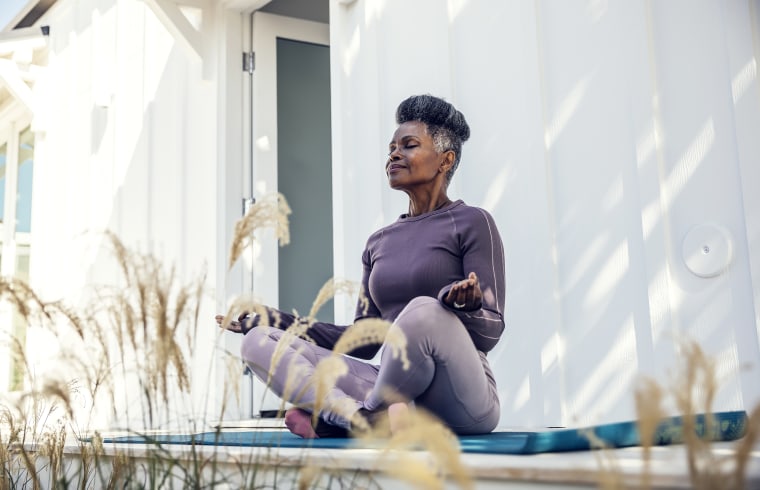 Woman meditating in backyard.