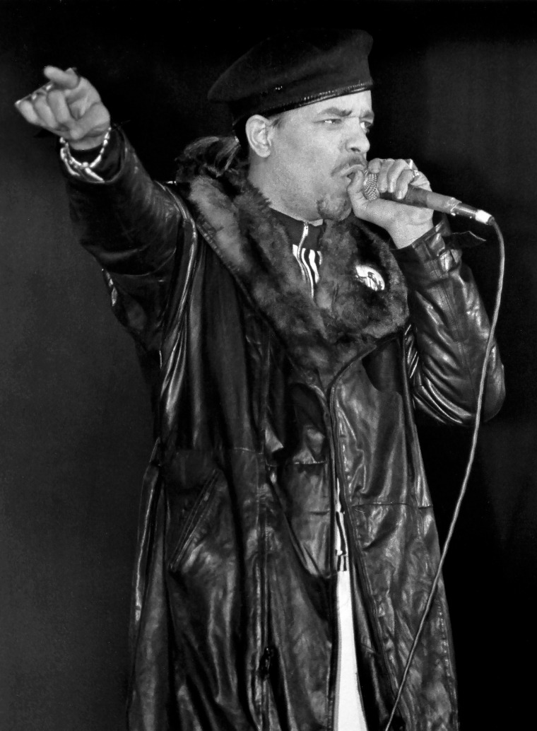 Ice-T holds a microphone while rapping at a concert.