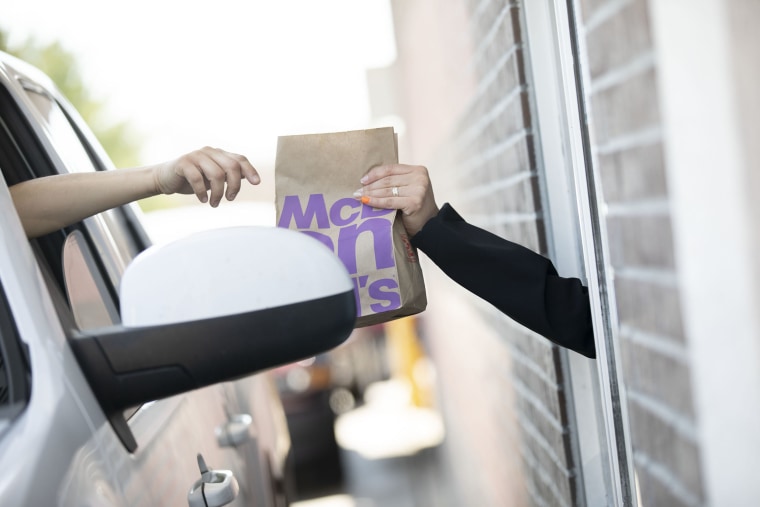 A customer reaches for a bag of food in the drive-through at a McDonald's Corp. restaurant in Peru, Illinois, U.S., on Wednesday, April 8, 2020. Some of America's fast-food workers are finally getting face masks and emergency sick days to help get them through the coronavirus outbreak.
