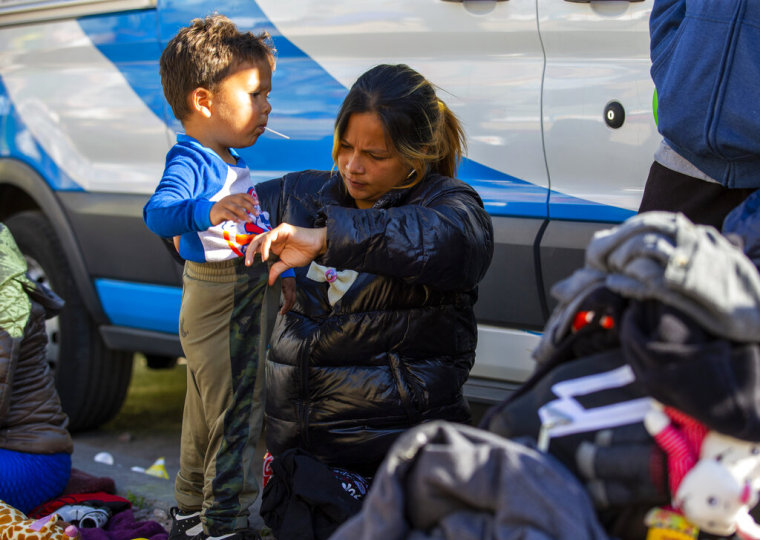 La migrante venezolana Karla Sainz, de 26 años, embarazada de ocho meses, ayuda a su hijo Joshua, de 2, a vestirse mientras acampa fuera de la Iglesia del Sagrado Corazón en el centro de El Paso, Texas, el domingo 8 de enero de 2023.