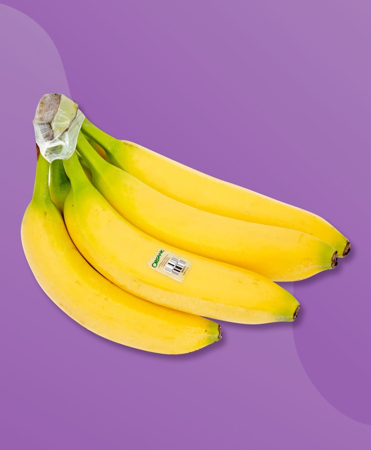 A hand of bananas on a purple background.