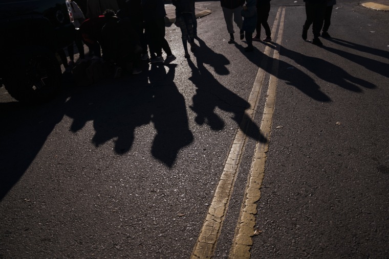 Migrants wait in line for food donations outside the Greyhound bus station near the U.S.-Mexico border in El Paso, Texas, on Dec. 21, 2022.