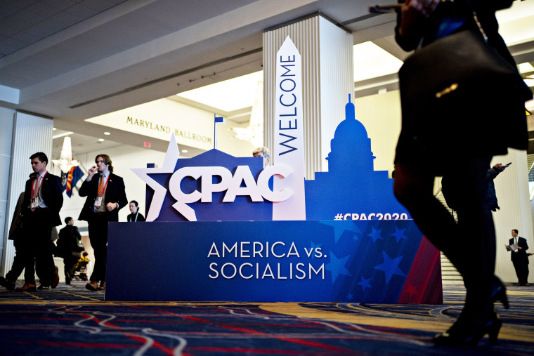 People walk past "America vs. Socialism" signage at CPAC
