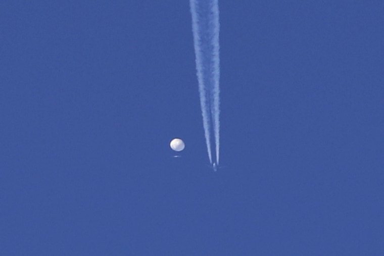 An airplane flies below a large balloon as it drifts above the Kingstown, NC