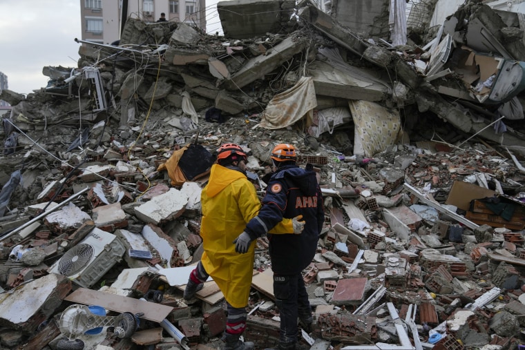 Emergency team members pause for a moment as they search for people in a destroyed building in Adana, Turkey