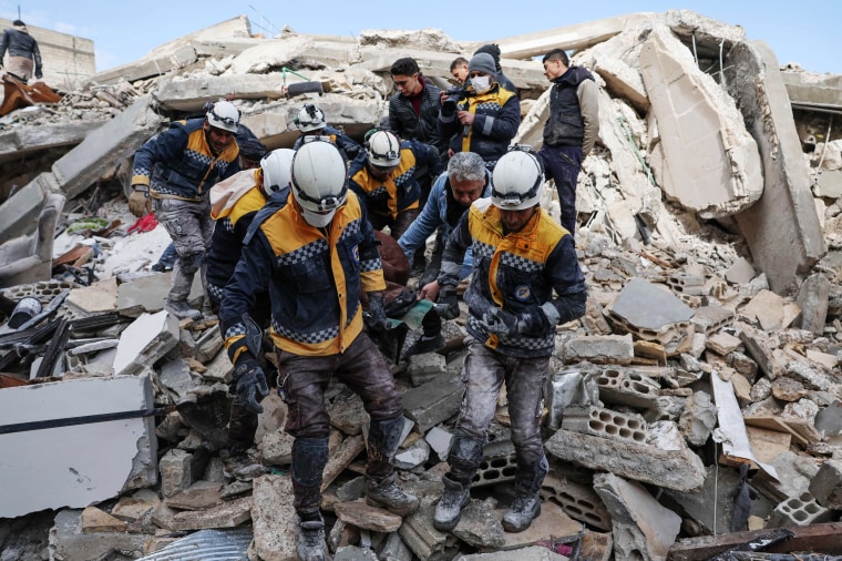 Members of the Syrian civil defense, known as the White Helmets, transport a casualty from the rubble of buildings in Azmarin in Syria's rebel-held northwestern Idlib province on Feb. 7, 2023. 
