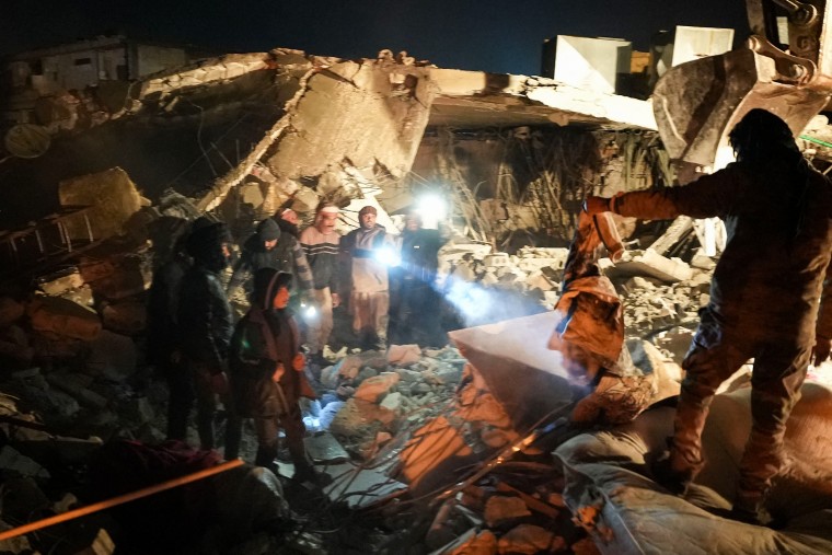 People search through the rubble of a house where a newborn baby was rescued alive on Feb. 6, 2023, in Jandaris, Syria.