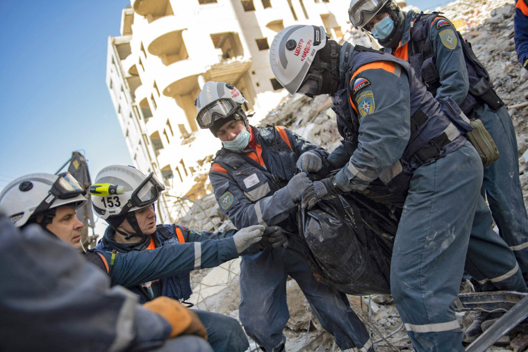 Russian rescue workers retrieve a body from the rubble of a collapsed building in the regime-controlled town of Jableh in Syria's Latakia province on Feb. 8, 2023.