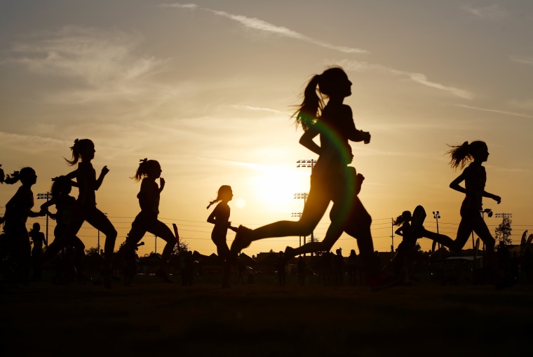 Runners compete in a 5k at sunset.