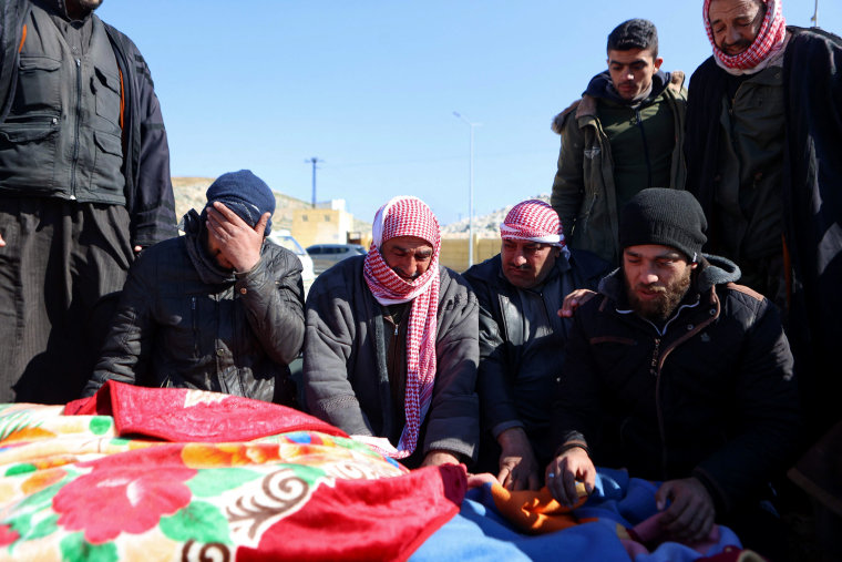 Image: Syrian men mourn as they identify a body of a relative killed in the earthquake after its arrival at the Bab al-Hawa border crossing near Syria and Turkey on Feb. 8, 2023.