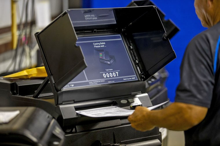 A Torrance County electoral worker introduces a ballot in a counting machine during a testing of election equipment in Estancia, N.M., on Sept. 29, 2022.