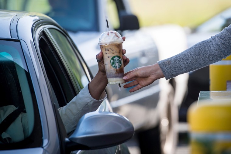 An employee passes a drink order to a customer at the drive-thru of a Starbucks Corp. coffee shop in Rodeo, California, U.S., on Monday, April 23, 2018. The world's largest coffee-shop chain is embracing the drive-thru lane. Eighty percent of all its new U.S. cafes will have them. 