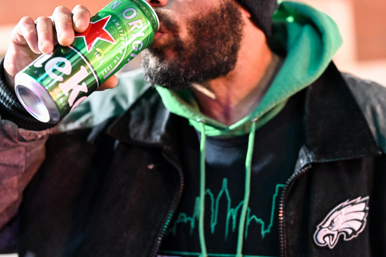 A street vendor drinks a beer while taking a break from selling Philadelphia Eagles themed apparel in Philadelphia on Feb. 7, 2023, in advance of the Super Bowl.