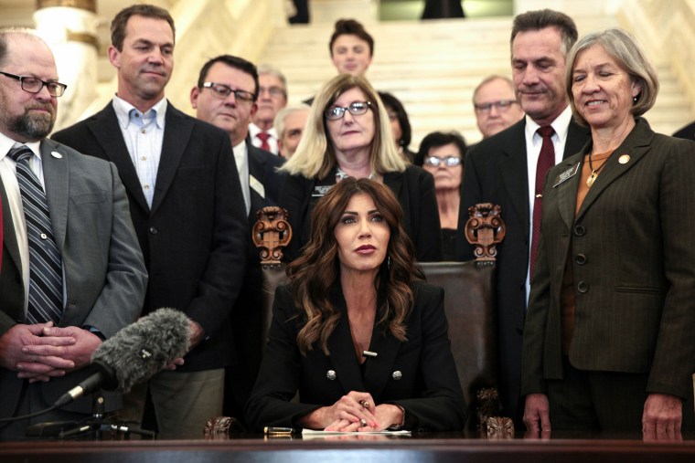 South Dakota Gov. Kristi Noem signs a bill on Feb. 3, 2022, at the state capitol in Pierre that will ban transgender women and girls from playing in school sports leagues that match their gender identity.