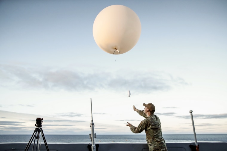 An Air Force member releases a weather balloon off the deck during the recovery operation for NASA's Orion Capsule and uncrewed Artemis I Moon Mission on Dec. 11, 2022 aboard the U.S.S. Portland in the Pacific Ocean off the coast of Baja California, Mexico.