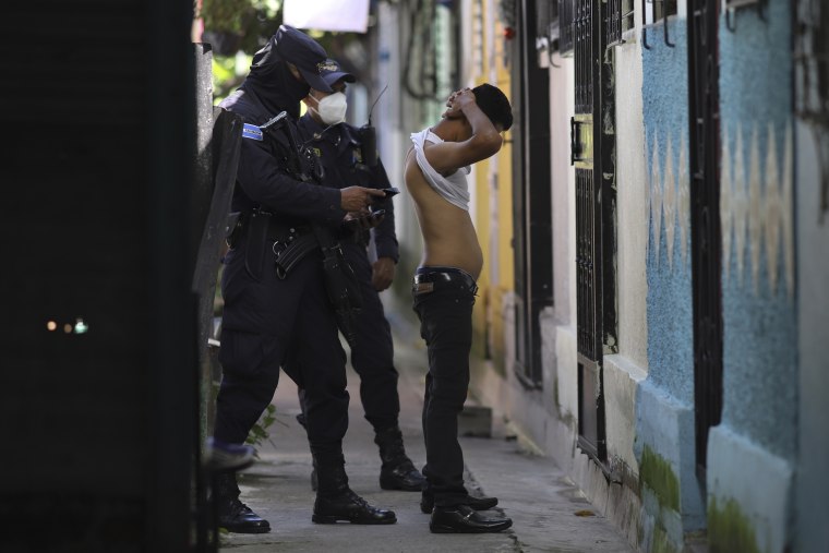 A police officer searches and checks the documents of a man during a preventive patrol in search of gang members in Soyapango, El Salvador