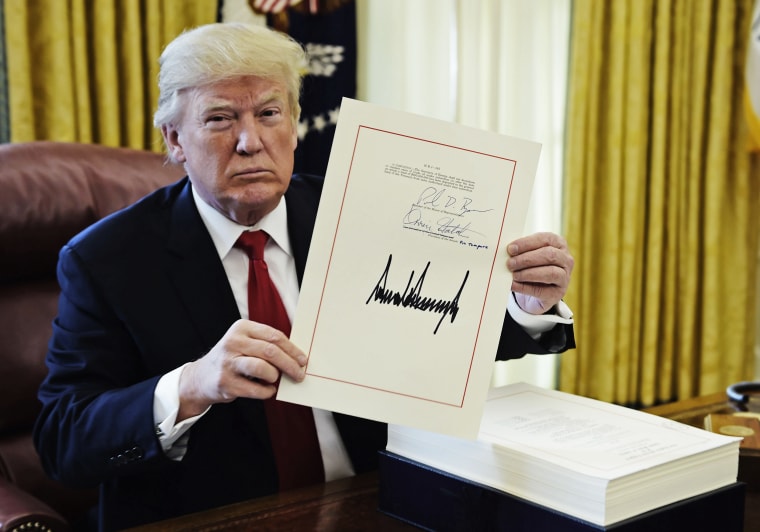 President Donald Trump holds up a document during an event to sign the Tax Cut and Reform Bill in the Oval Office on Dec. 22, 2017.