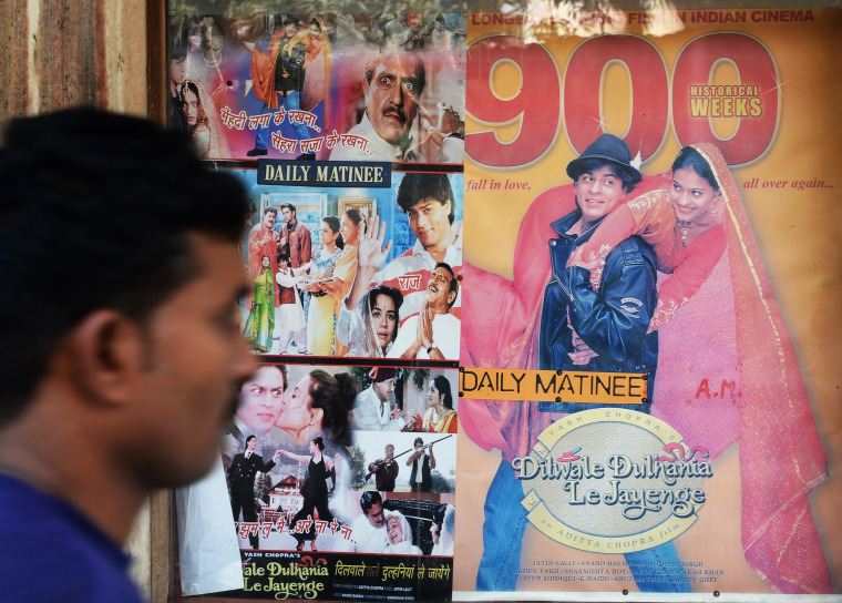 A cinemagoer walks past movie posters the popular Bollywood Hindi film 'Dilwale Dulhania Le Jayenge'  in Mumbai