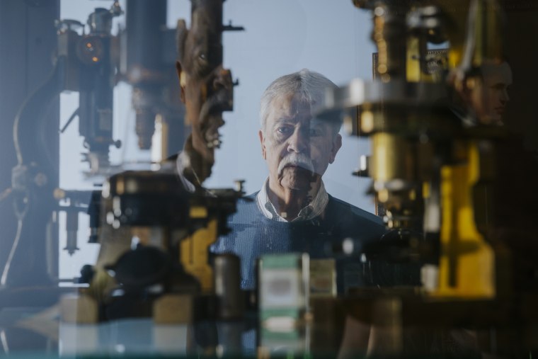 Skip Palenik is reflected in a display case of microscopes at Microtrace LLC in Elgin, Ill. 