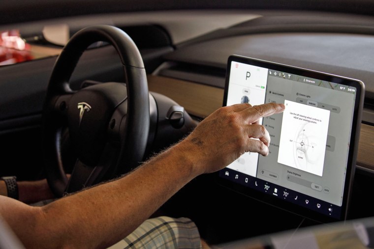 A customer uses the touch screen display in a Tesla Model 3 electric vehicle at the company's showroom in Newport Beach, Calif., on July 6, 2018.