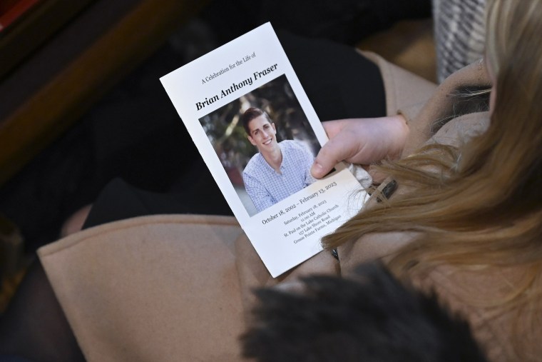 Loved ones hold funeral mass programs with a portrait of Brian Fraser in Grosse Pointe Farms, Mich.