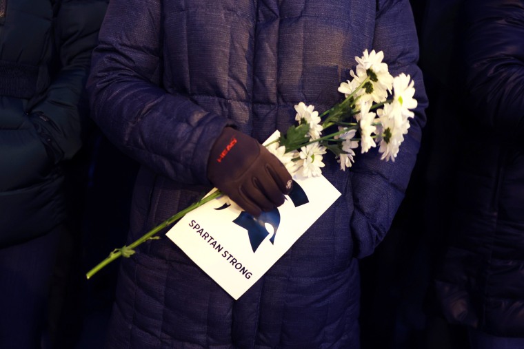 A person holds flowers during a vigil on the campus of Michigan State University