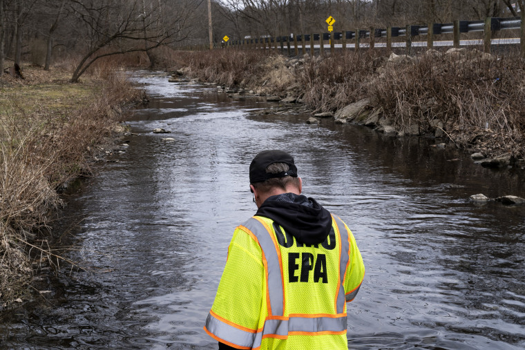 An EPA Emergency Response worker checks for chemicals that have settled at the bottom of a creek in East Palestine, Ohio