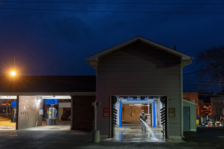 Ron Rafferty Jr. 60, wears a mask while pressure washing to clean the floor of a car wash in East Palestine, Ohio,