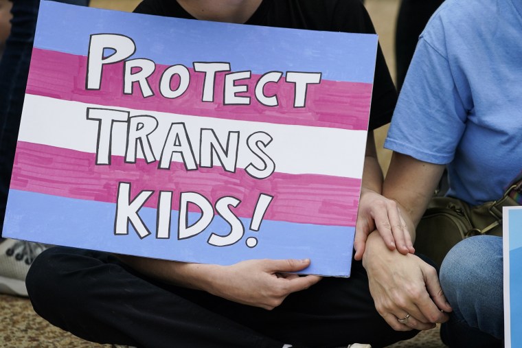 A protester holds a poster calling for lawmakers to protect trans children by voting against House Bill 1125, which would ban gender-affirming care for trans children, at the Mississippi Capitol in Jackson on Feb. 15, 2023.