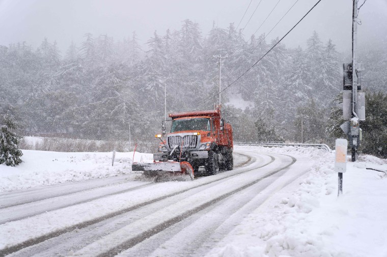 A plow clears snow on Mount Baldy Road in the town of Mount Baldy, California, on February 24, 2023. - Californians more used to flip flops and shorts were wrapping up warm Thursday as a rare winter blizzard, the first in more than 30 years, loomed over Los Angeles, even as the US East Coast basked in summer-like temperatures.