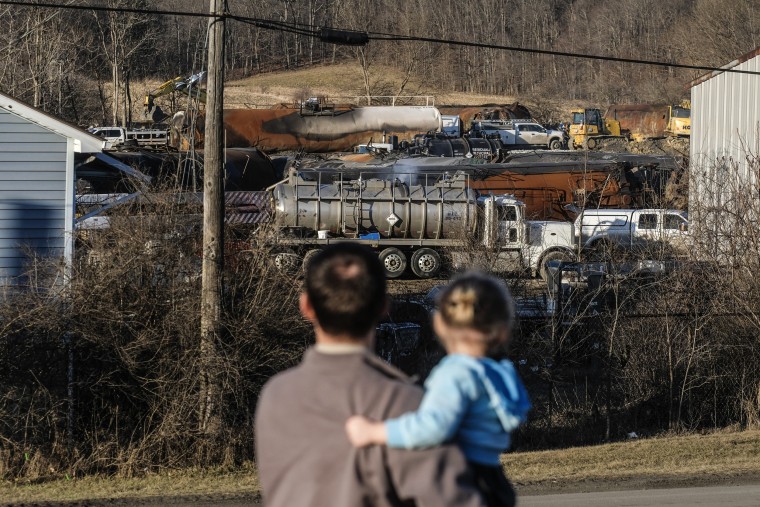 A family from Pennsylvania inspects the wreckage of the Norfolk Southern train derailment in East Palestine, Ohio on Feb. 19, 2023.