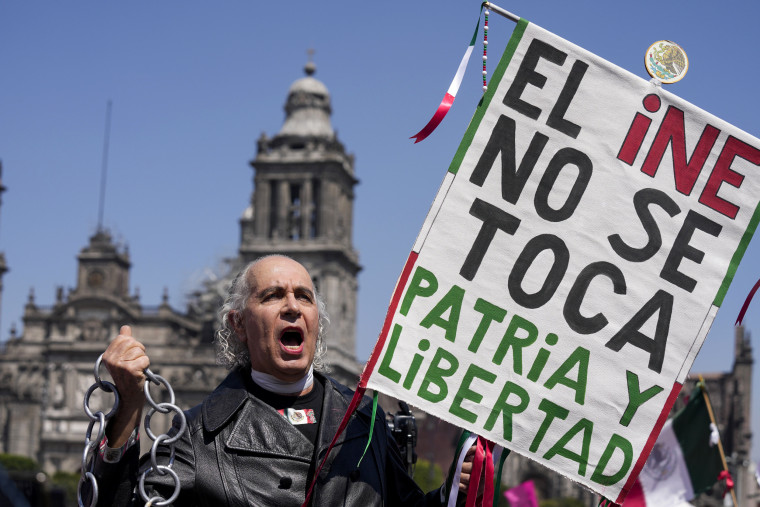 A protester dressed as independence hero Miguel Hidalgo holds a sign that reads in Spanish "Do not touch the INE, Motherland and Freedom," during a march against recent electoral reforms pushed by President Andres Manuel Lopez Obrador in Mexico City on Feb. 26, 2023.