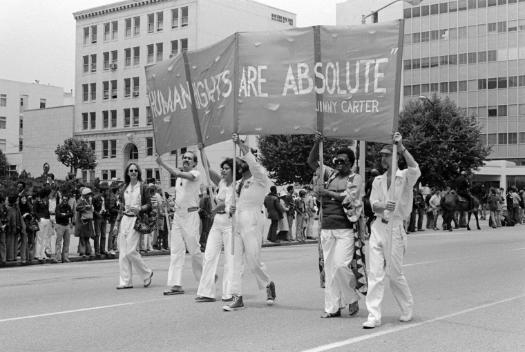 Os manifestantes da Parada da Liberdade Gay carregam uma faixa com uma citação de Jimmy Carter em 26 de junho de 1977.