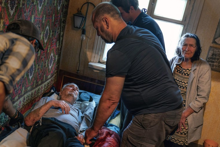 Lidia Mariukha, de 79 años, a la derecha, llora mientras ve a su marido,  Viktor, de 84 años, mientras es puesto en una cama por miembros del grupo de ayuda Refugease, que los ha evacuado de su casa en Kramatorsk, en la región de Donetsk, ante los ataques, el 2 de agosto de 2022. 