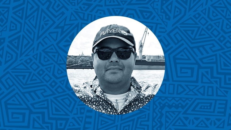 Una foto en blanco y negro de un hombre latino con gorra y lentes frente a un muelle. El fondo es una ilustración de garigoleos en colores azules