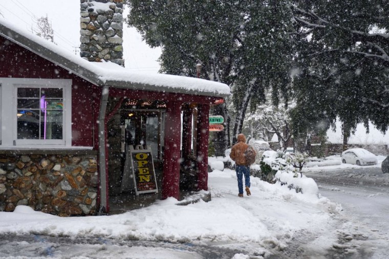 Un hombre pasa por delante del restaurante Mt. Baldy Lodge mientras cae una intensa nevada en la localidad de Mount Baldy, California,el 24 de febrero de 2023.