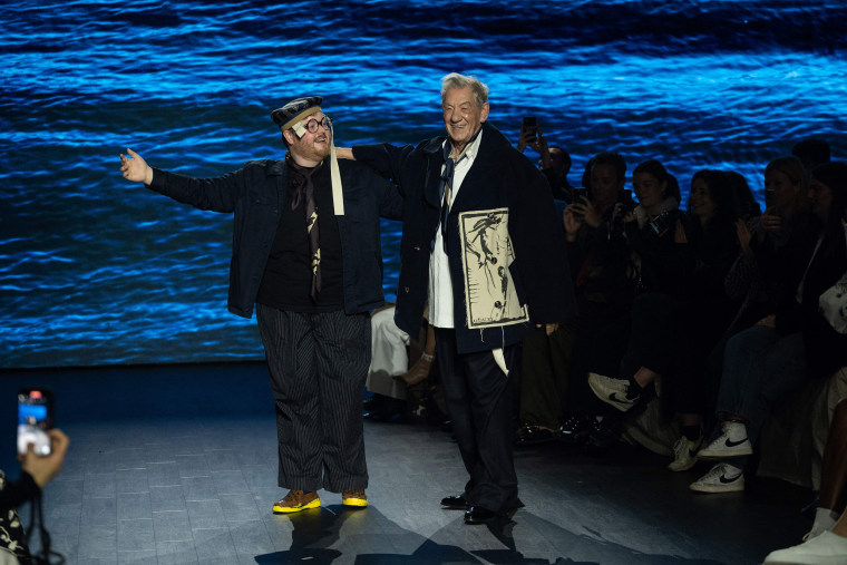 British fashion designer Steven Stokey-Daley (L) and British actor Ian McKellen acknowledge the crowd after Stokey-Daley presented his attends fashion label S.S.Daley's Autumn/Winter 2023 collection catwalk show on the third day of the London Fashion Week, in London, on February 19, 2023.