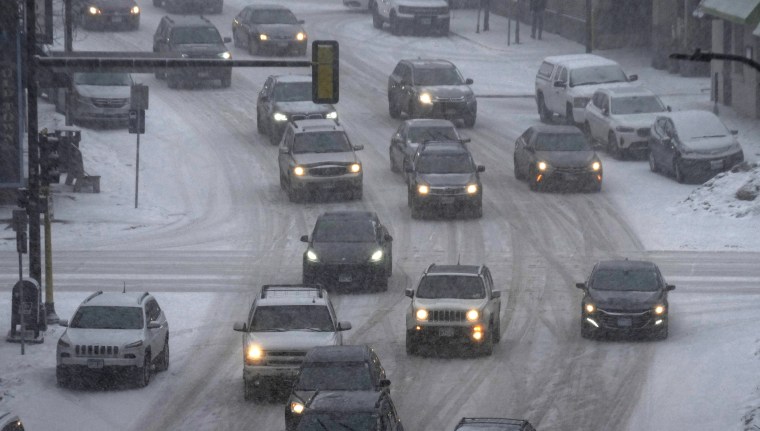 Vehículos circulan por el centro de Minneapolis mientras cae la nieve, martes 21 de febrero de 2023.
