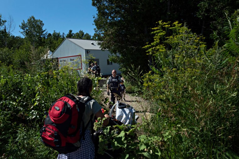 Migrantes cruzan la frontera con Canadá al final de Roxham Road, en una foto de archivo de julio de 2018.