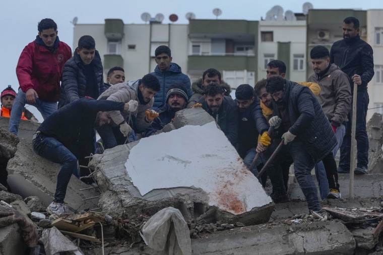 Varios hombres buscan personas entre los escombros de un edificio destruido en Adana, Turquía, el lunes 6 de febrero de 2023.