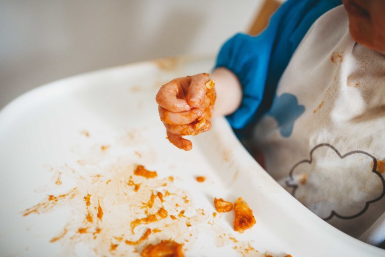 Close up of a baby's hands while eating and making a mess
