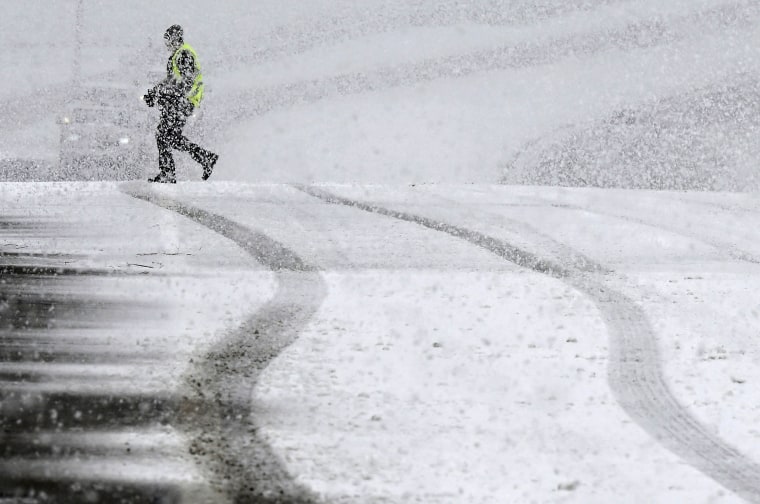 A pedestrian walks across the Highway 38 overpass above I-15 in the California Cajon Pass as heavy snow falls, on Thursday, Feb. 23, 2022.