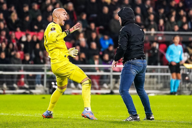 Marko Dmitrovic of Sevilla FC attacked by a supporter who invaded the pitch during the UEFA Europa League Knockout Round Play-Off Leg Two match between PSV and Sevilla FC.