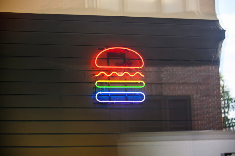 The Shake Shack logo is lit in pride colors.