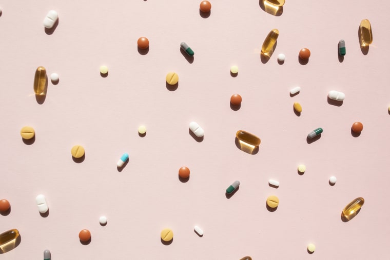Top view of various pills and tablets on the pink background